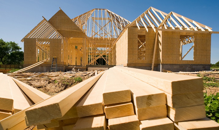 An image of a new home under construction, with lumber in the foreground.